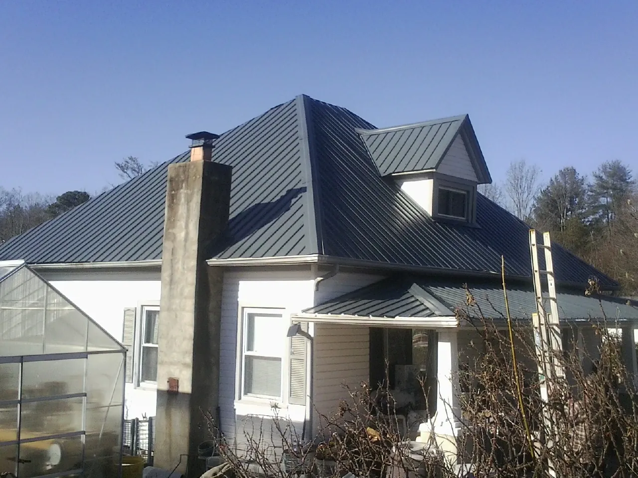Dark blue standing seam metal roof on a white farmhouse with dormer — Slate & Tile Roof Repair by Roofing Brothers in Reelsville