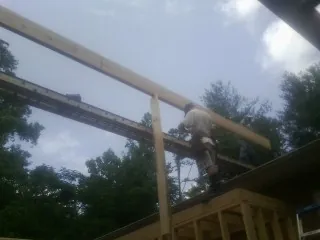 Carpenter setting a ridge beam over a new addition frame — Ice Dam Removal by Roofing Brothers in Reelsville
