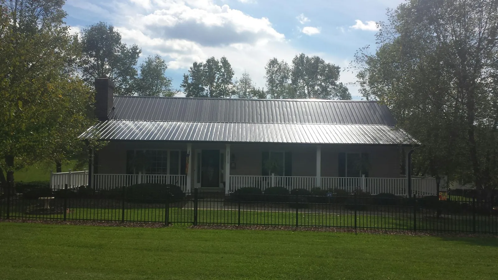 Gray metal roof on a brick ranch with a full width front porch — Gutter Guard Installation work by our crew in Reelsville