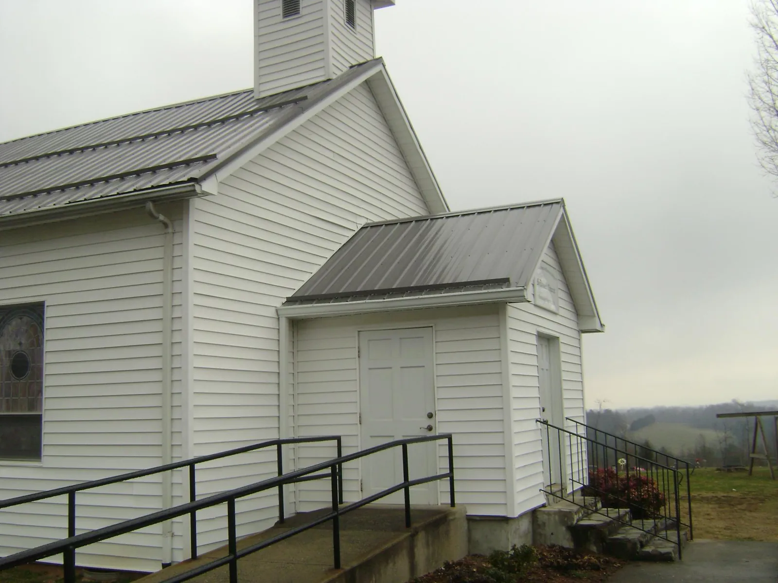 Gray metal roof on a white clapboard church with a steeple in Reelsville