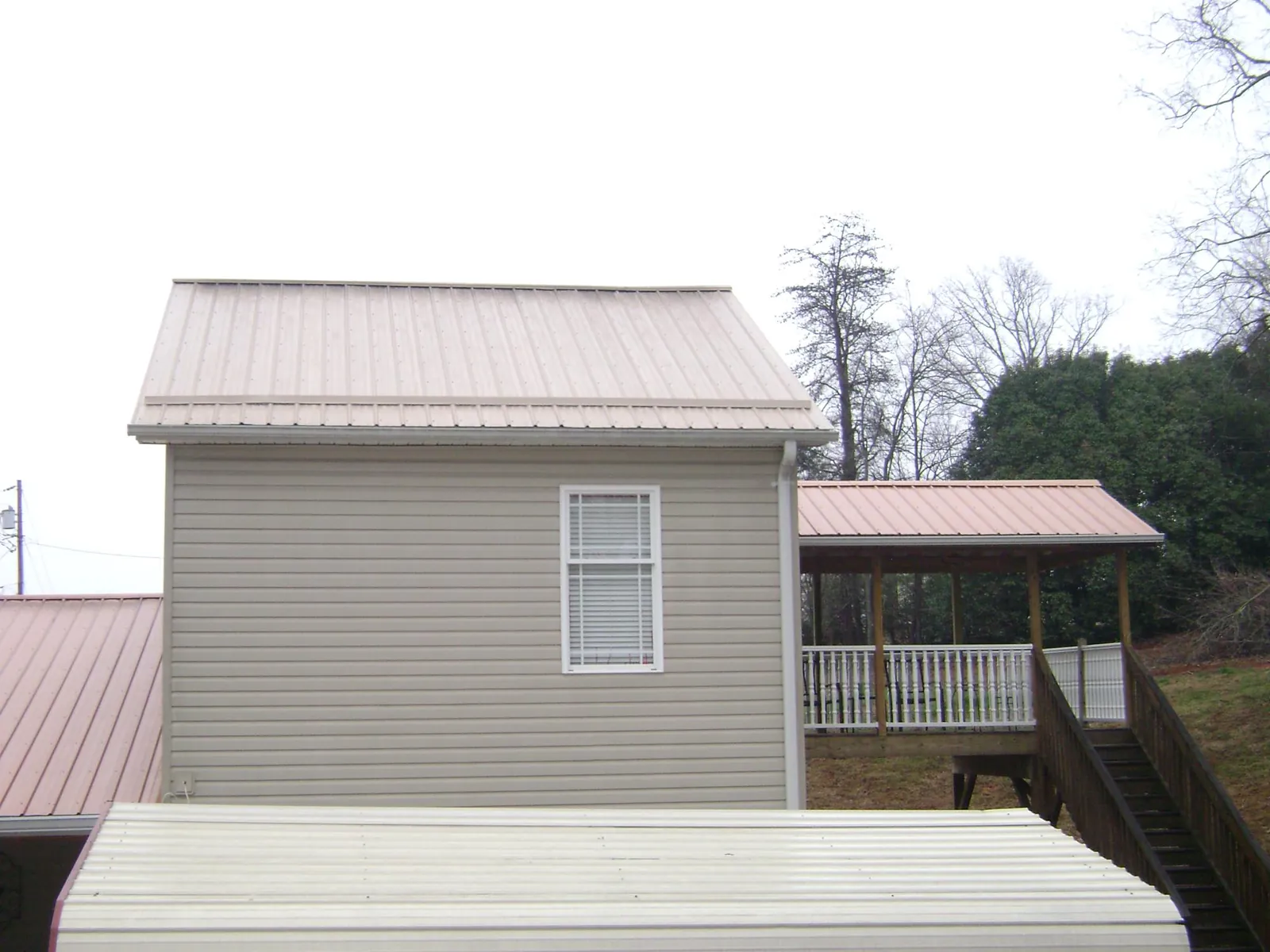 Tan metal roofs on a two story addition and attached porch, from a Roof Replacement job in Reelsville