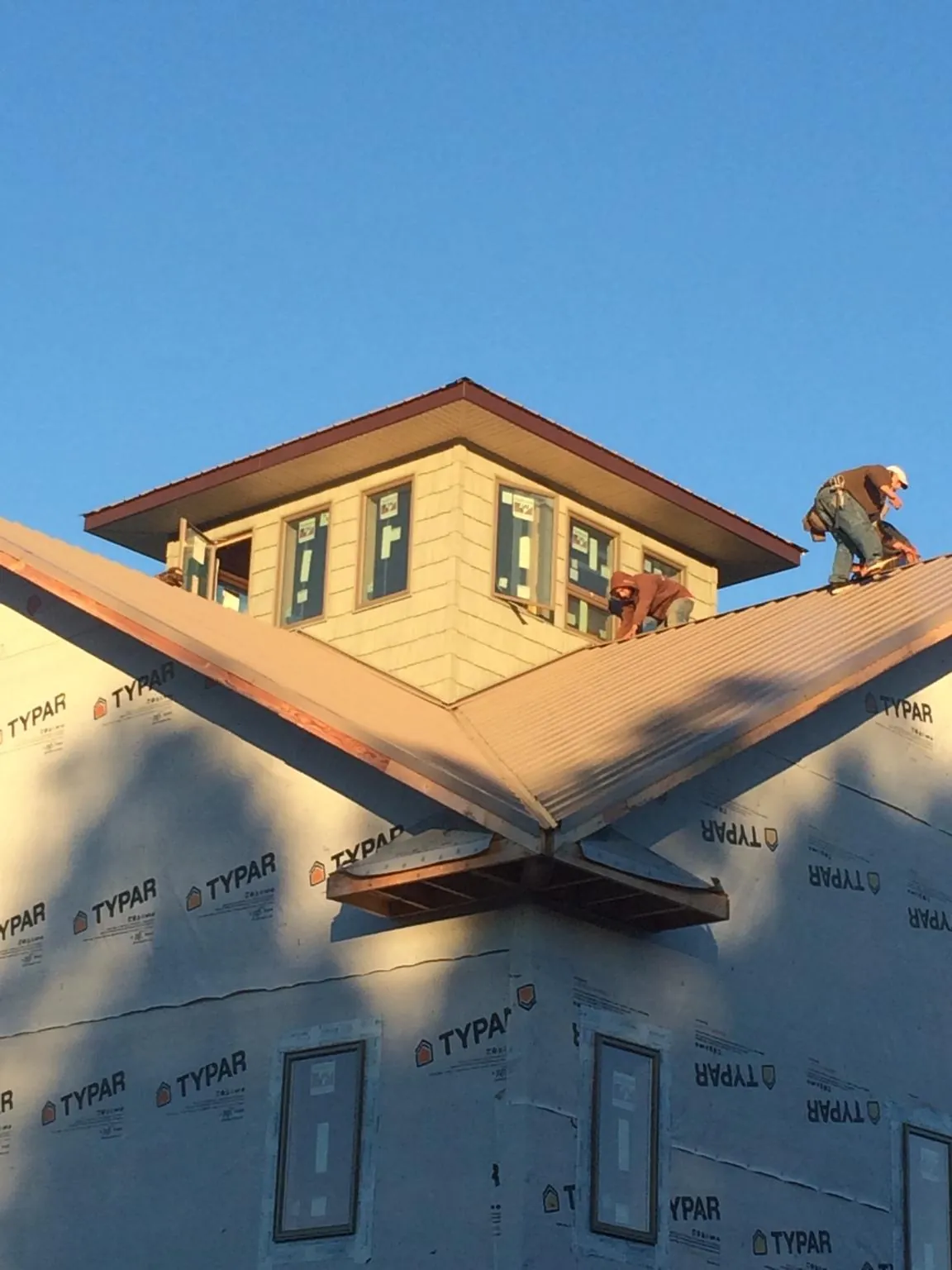 Roofers working around a rooftop cupola on a new metal roof at sunset — Roof Waterproofing in Reelsville by Roofing Brothers